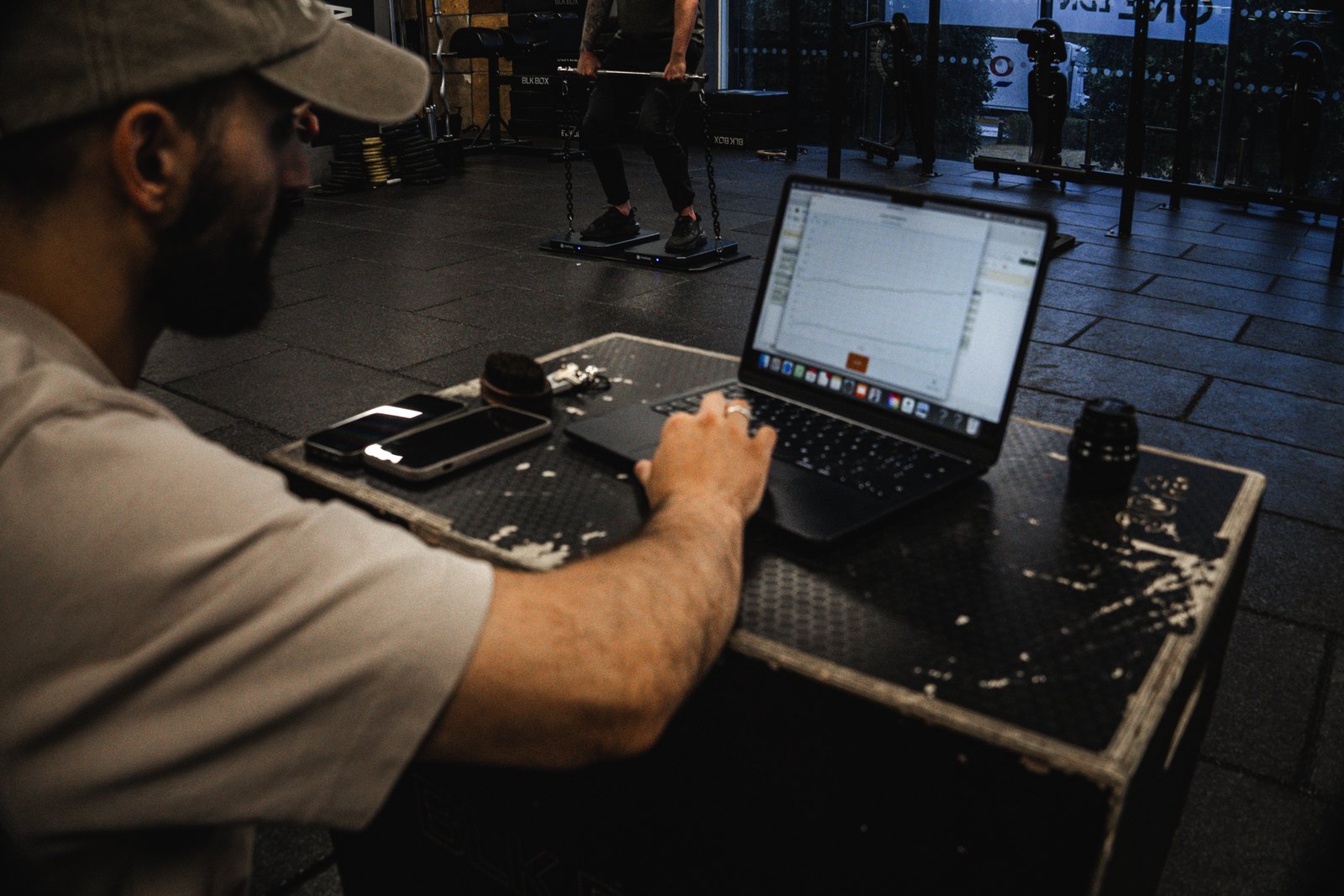 Coach reviewing live force-plate data on a laptop during a testing session